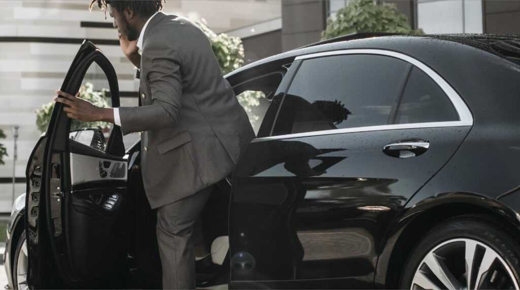 Business executive getting into a luxury black chauffeur car for airport transfer in Vietnam